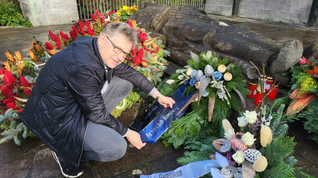 Vorstand Matthias Rühr korrigiert die Schmuckschleife am Kriegerdenkmal